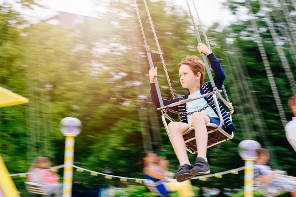 Menino feliz se divertindo no parque de diversões . — Fotografia de Stock