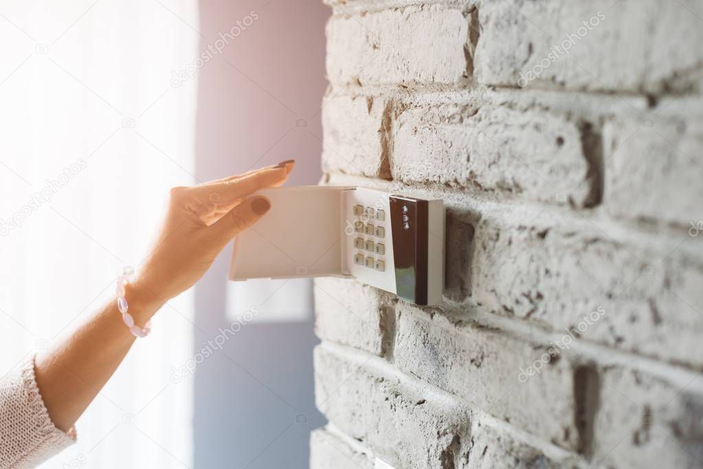 Woman entering password on home alarm keypad.