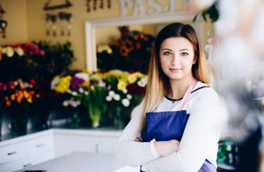 Çiçekçi dükkanı çapraz kolları olan kendine güvenen genç kadın sahibi