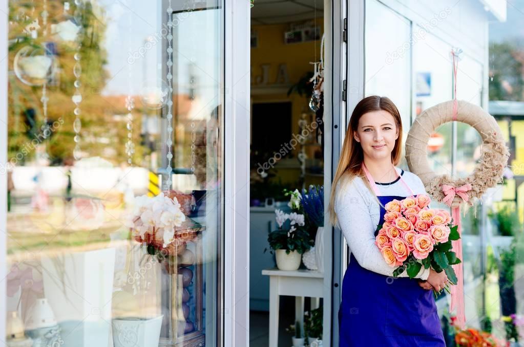 Woman owner of florist shop with bunch of roses.