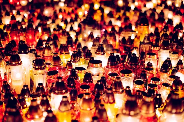 Burning colourful candles on cemetery at night.