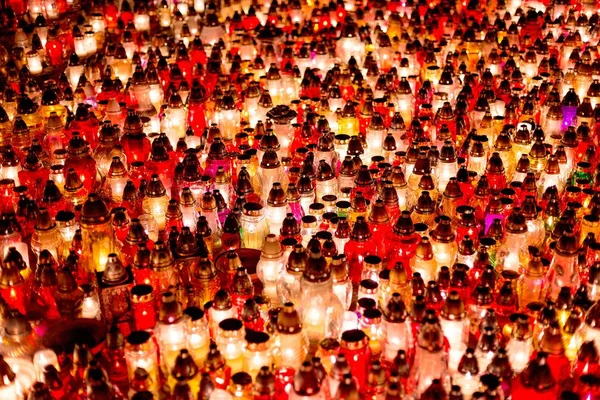 Burning colourful candles on cemetery at night.