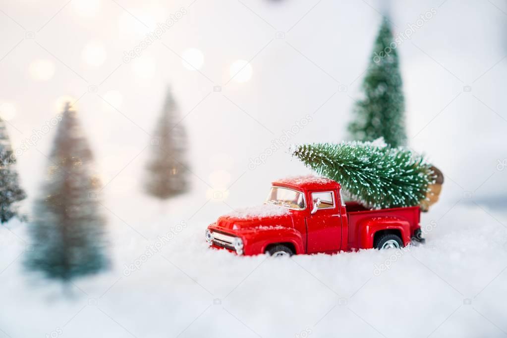 Red toy pickup car carrying Christmas tree