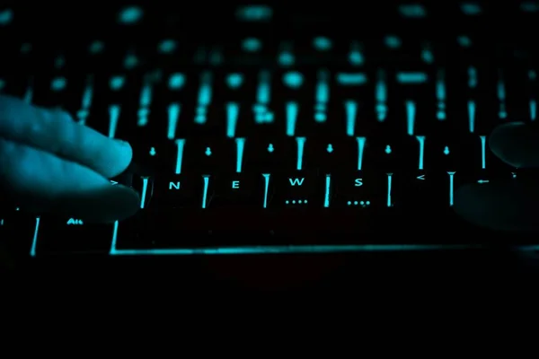 Notícias - texto no teclado do computador iluminado à noite — Fotografia de Stock