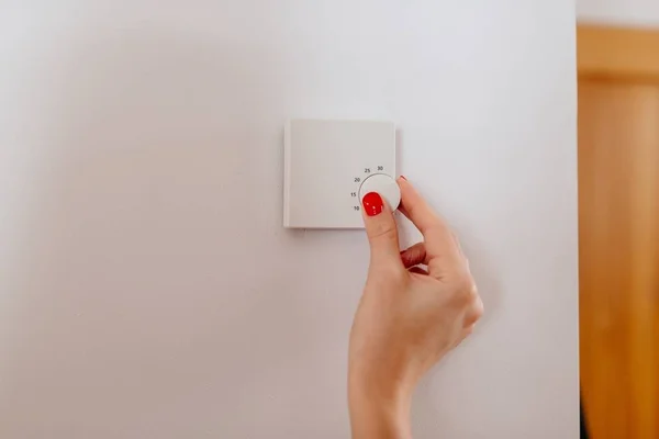 Donna che regola la temperatura sul termostato per riscaldamento domestico — Foto Stock