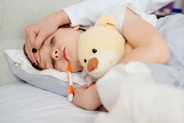 Doente menino de oito anos na cama com um termômetro — Fotografia de Stock