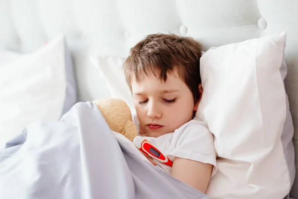 Chłopczyk chory w łóżku z termometrem — Zdjęcie stockowe