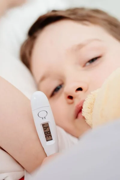 生病的男婴在床上的温度计 — 图库照片
