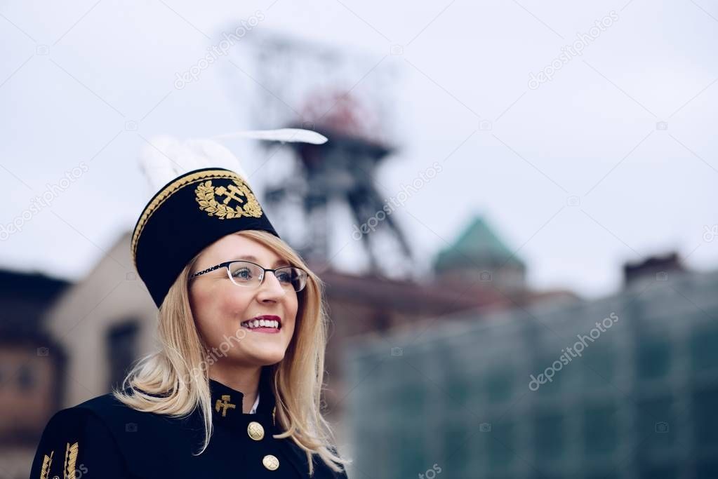 Woman in black coal miner foreman gala uniform with white feather on hat.