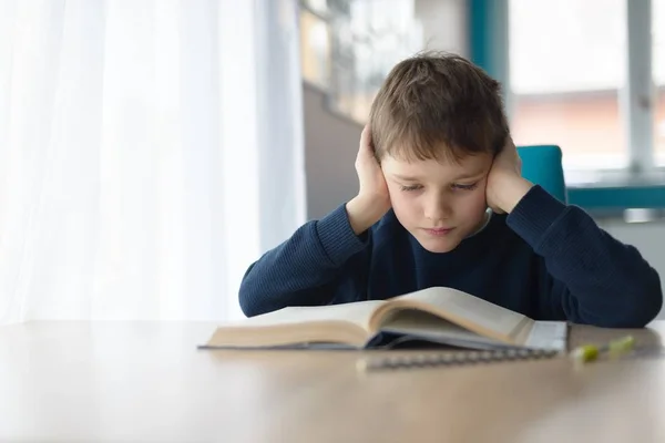 Criança lendo um livro na mesa — Fotografia de Stock