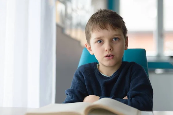 Müder 8-jähriger Junge macht seine Hausaufgaben am Tisch — Stockfoto