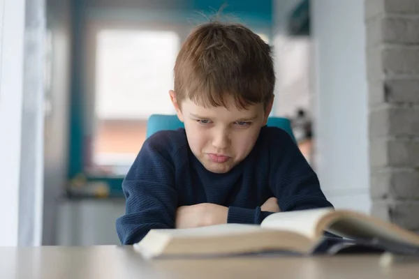 Fatigué 8 ans garçon faire ses devoirs à la table — Photo