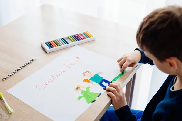 Feliz niño de 8 años dibujando una tarjeta de felicitación para su abuela —  Fotos de Stock