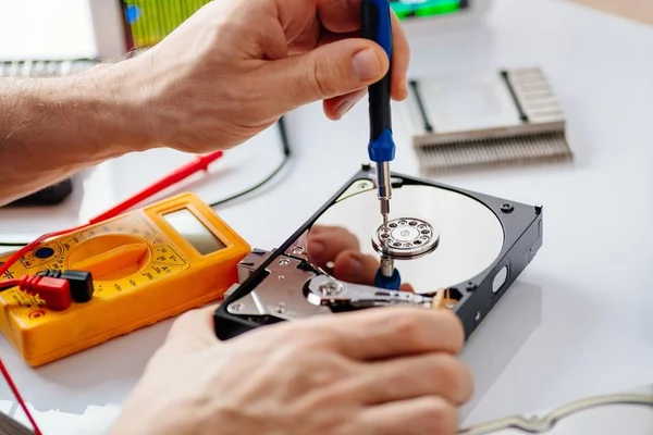 Technician repairing broken hard disk drive.