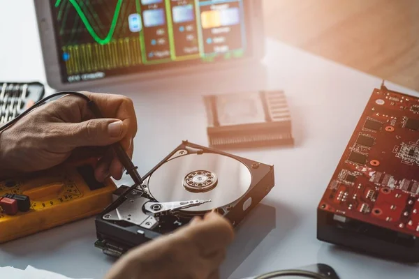 Technician repairing broken hard disk drive.