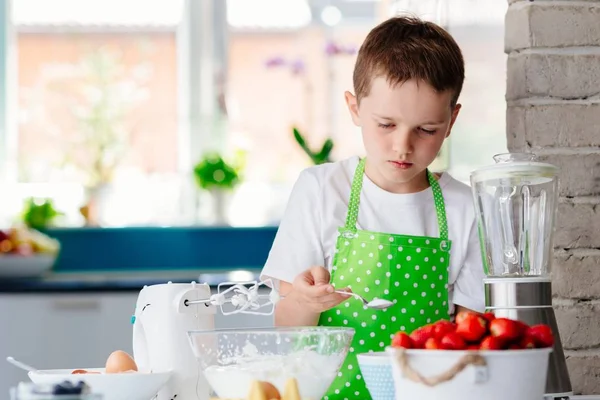 Gelukkig kind jongen toevoegen van suiker aan de kuip en het voorbereiden van een taart. — Stockfoto
