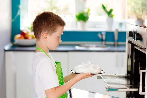 Счастливый ребенок кладет торт в духовку — стоковое фото