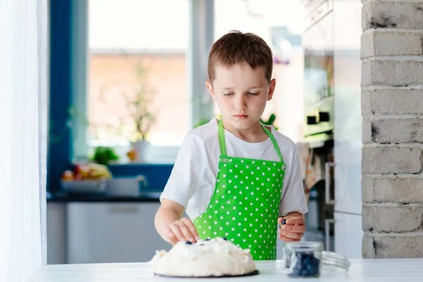 Feliz niño decorando merengue con arándanos — Foto de Stock