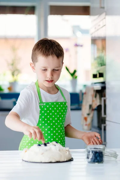 Feliz niño decorando merengue con arándanos —  Fotos de Stock