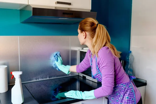 Mladá žena v gumové rukavice čištění kuchyně. — Stock fotografie