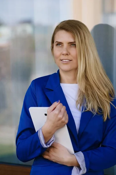 Fiatal elegáns üzleti nő a gazdaság tabletta kék kabát. — Stock Fotó