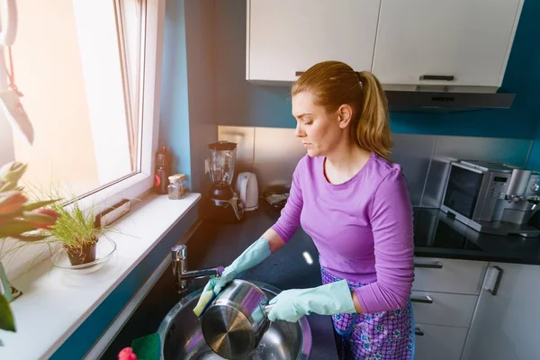 Young woman in rubber gloves washing dishes — Stock Photo, Image