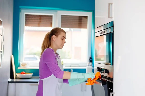 Young woman in rubber gloves cleaning oven — Stock Photo, Image