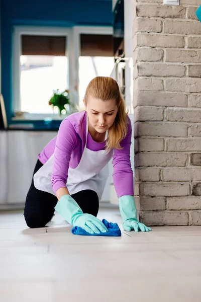 Giovane donna in grembiule bianco lavare pavimento sulle ginocchia . — Foto Stock