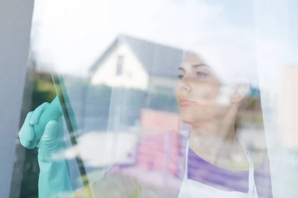 Mladá krásná žena v bílé zástěře cleaing windows. — Stock fotografie