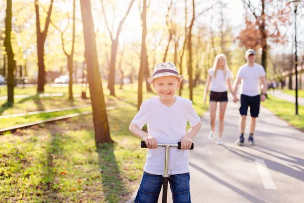 Enfant garçon équitation sur scooter dans le parc . — Photo