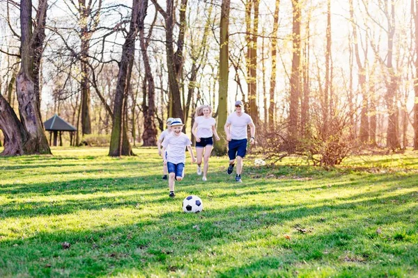 Família jogando futebol na grama verde no parque . — Fotografia de Stock
