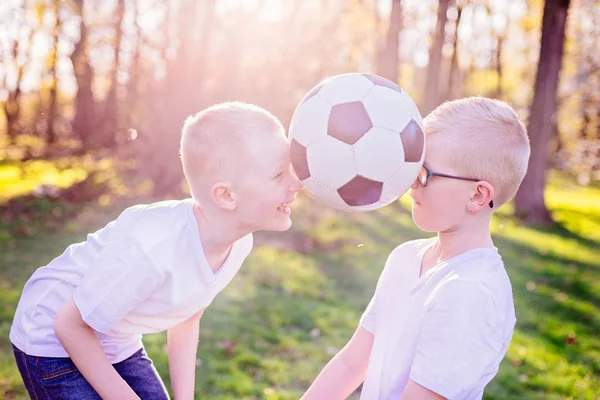 Pojkar bröder leker med boll på grönt gräs i parken. — Stockfoto