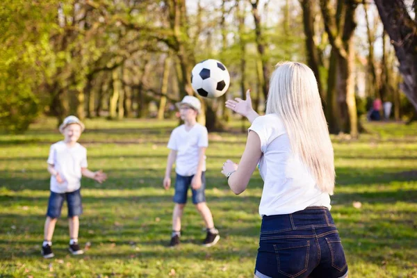 Madre jugando con pelota con sus hijos en la hierba verde en el parque . — Foto de Stock
