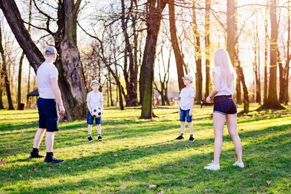 Οικογένεια που ρίχνει την μπάλα στο πράσινο γρασίδι στο πάρκο. — Φωτογραφία Αρχείου