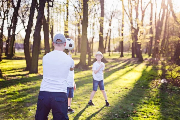 Familjen kastar bollen på grönt gräs i parken. — Stockfoto