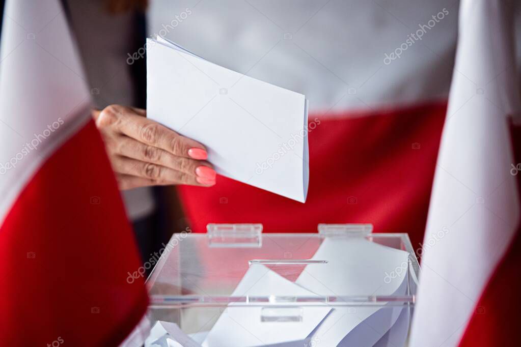 Woman putting her vote to ballot box. Poland political elections