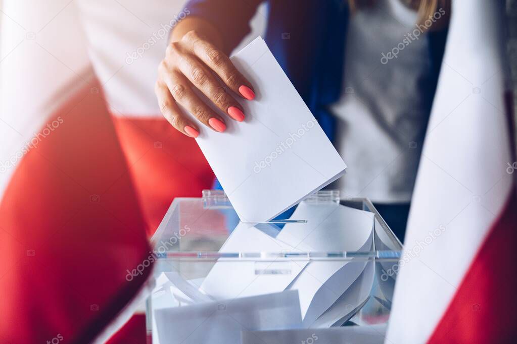 Woman putting her vote to ballot box. Poland political elections
