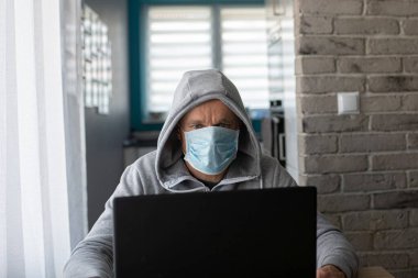 Evde tıbbi maskeli bir adam çalışıyor. Merkez Ofis