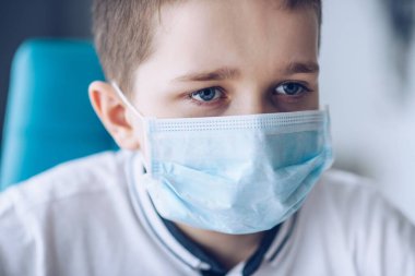 Tıbbi koruyucu maskeli üzgün çocuk. Koronavirüs salgını sırasında çocuk