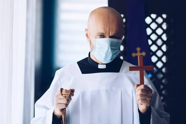 Homme prêtre en masque médical priant avec croix et chapelet . — Photo