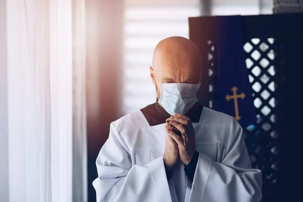 Homem sacerdote em máscara médica rezando com cruz e rosário . — Fotografia de Stock