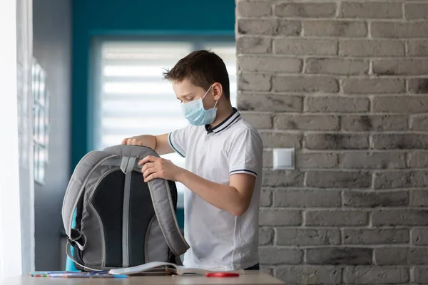 Niño en cuarentena empacando sus libros en la mochila de la escuela . — Foto de Stock