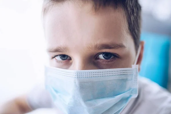 Droevige jongen met medisch beschermend masker. Kind tijdens de coronavirusepidemie — Stockfoto