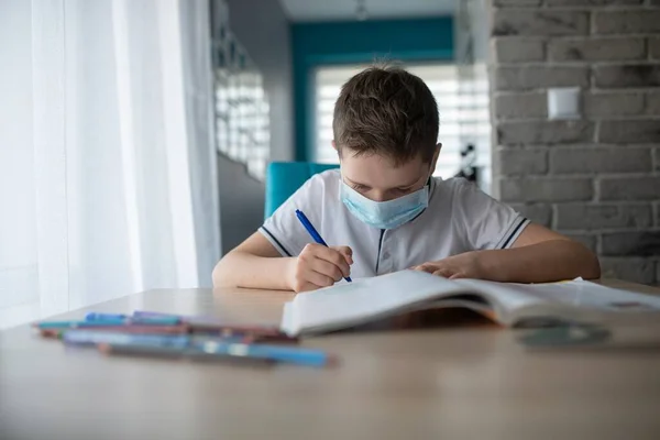 과보호 마스크를 쓴 아이가 숙제를 하고 있습니다. 코로나 바이러스때문에 학교 가문을 닫다 — 스톡 사진