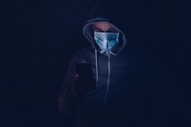 Korkmuş bir adam akıllı telefondan covid-19 koronavirüs hakkında bilgi okuyor. Coronavirus covid-19 salgını sırasında maskeli bir adam..