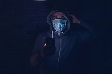 Korkmuş bir adam akıllı telefondan covid-19 koronavirüs hakkında bilgi okuyor. Coronavirus covid-19 salgını sırasında maskeli bir adam..