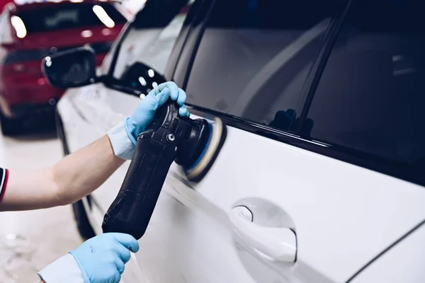 Man polishing car paint varnish in detailing studio