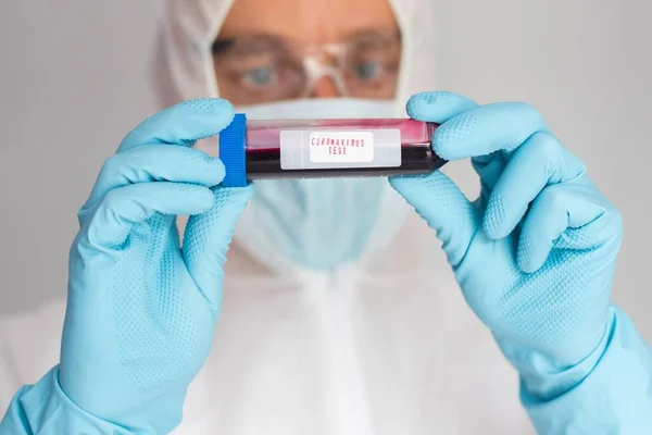 Científico en traje protector sosteniendo tubo de ensayo con sangre — Foto de Stock