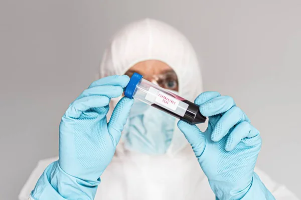 Científico en traje protector sosteniendo tubo de ensayo con sangre — Foto de Stock