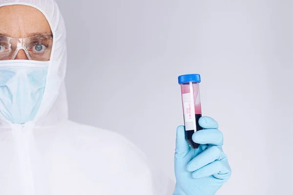 Wissenschaftler im Schutzanzug hält Reagenzglas mit Blut — Stockfoto